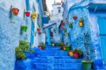 Blue-painted steps and colourful flower pots in a lane of Chefchaouen