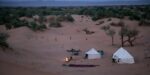 White desert camp tents among the dunes at dusk